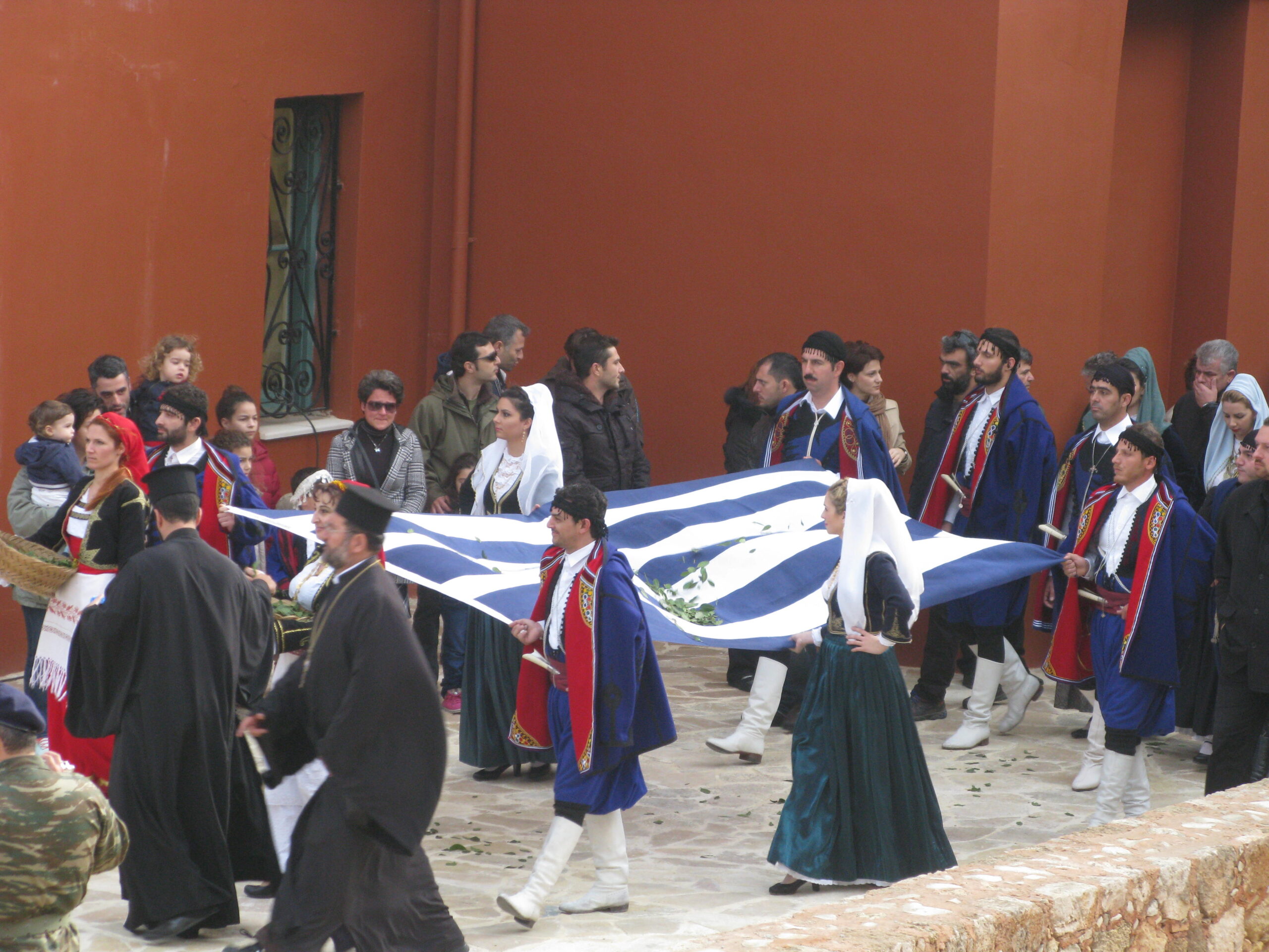 Η Ελληνική σημαία που υφάνθηκε με φυσικό μετάξι από υφάντριες-μέλη της Αποστολής Πηνελόπη Gandhi, υψώνεται στις 1 Δεκεμβρίου 2013, στο Φρούριο Φιρκά των Χανίων, για την επέτειο των 100 χρόνων της Ένωσης